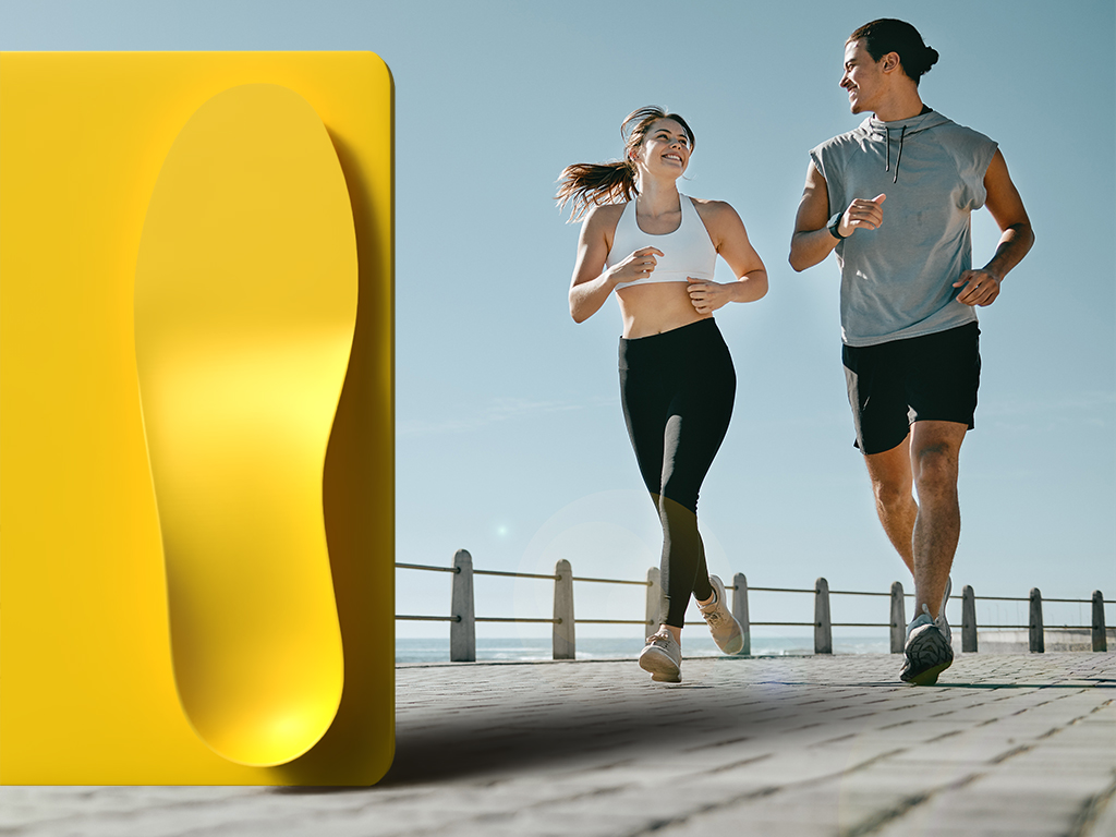 A yellow INSITE Levation insole imposed over an image of a man and a woman running on a boardwalk.